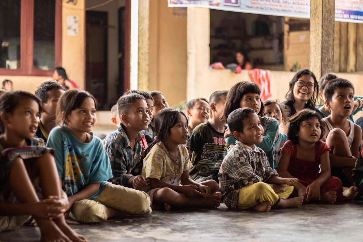 A group of children gathered together, smiling and listening
