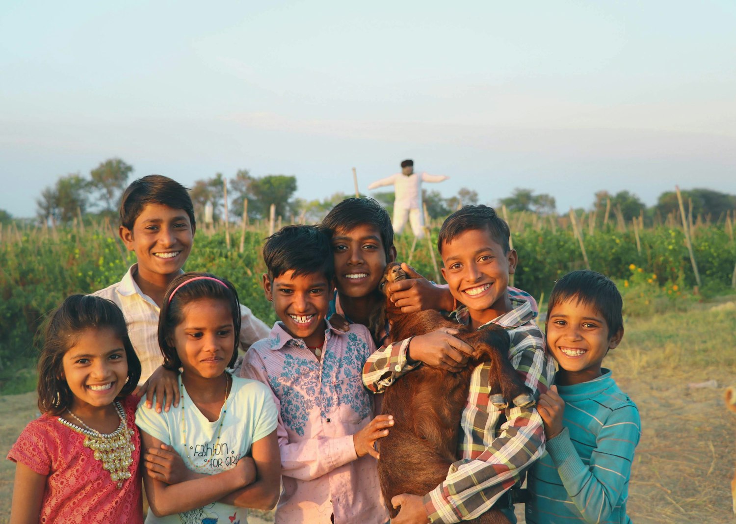A group of smiling children together outdoors in rural India at sunset